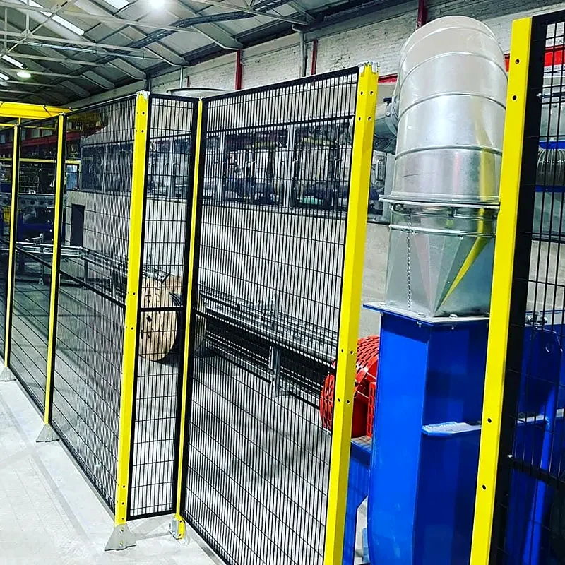 Black mesh panels with yellow posts beside industrial equipment and metal ducting.