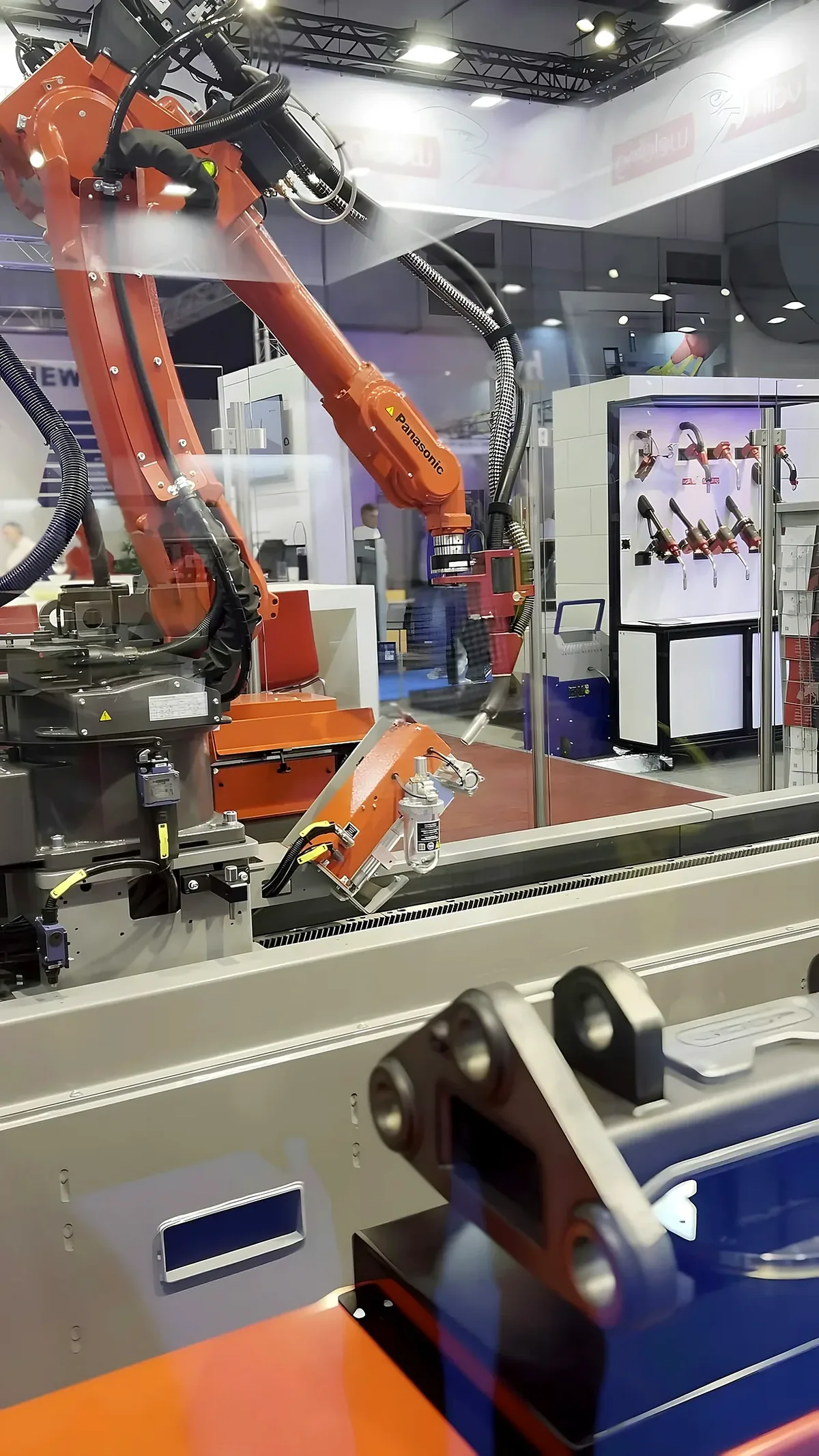 Orange robot arm and tooling behind a clear panel.
